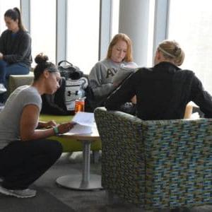 Students sitting around small table in the library